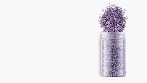 A pack of purple glitter crystal salt for aroma spa. Shimmering sea salt isolated on white background. Can of purple bath salt. The idea of home relaxation, aromatherapy and self care. Copy space.
