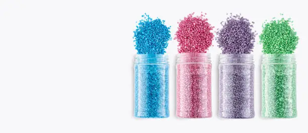A set of cans with multicolored glitter crystal salt for aroma spa. Shimmering sea salt jars isolated on white background. The idea of home relaxation, aromatherapy and self care. Copy space.