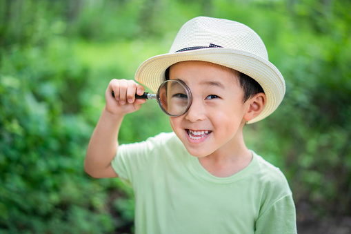 A baby holding magnifying glass to observe plants