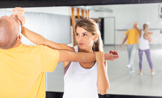 Young woman paired up with male partner in self defense training, practicing basic palm strike