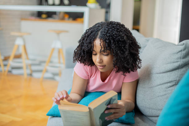 istock Happy woman reading book at home 1408322073