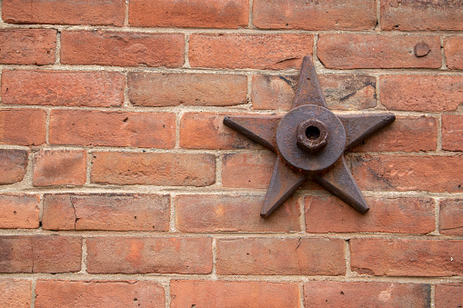 decorative and structural metal bolted stars on older brick building which suport the wall