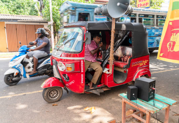 Tuk Tuk motorized rickshaw tricycle taxi with sound equipment is providing music for people who are celebrating Gotabaya Rajapaksa winning the Presidential Elections in Sri Lanka with the street festival in the local community in Hikkaduwa. Hikkaduwa, Sri Lanka - November 18, 2019: People celebrate Gotabaya Rajapaksa winning the Presidential Elections on the street festival in the local community. Tuk Tuk motorized rickshaw tricycle taxi with sound equipment is providing music. taxi sri lanka stock pictures, royalty-free photos & images