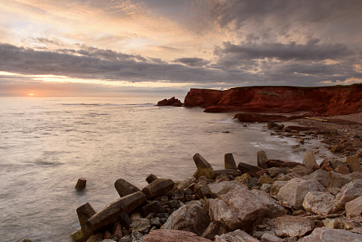 Red cliff and rocks of Magdalen Islands at sunset, Quebec