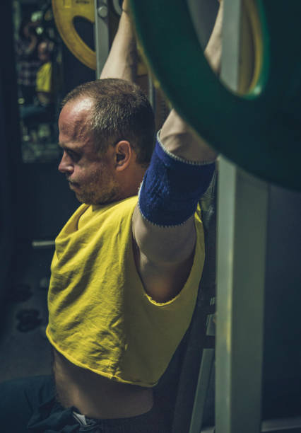 Adult man trains deltoid muscles at the smith machine