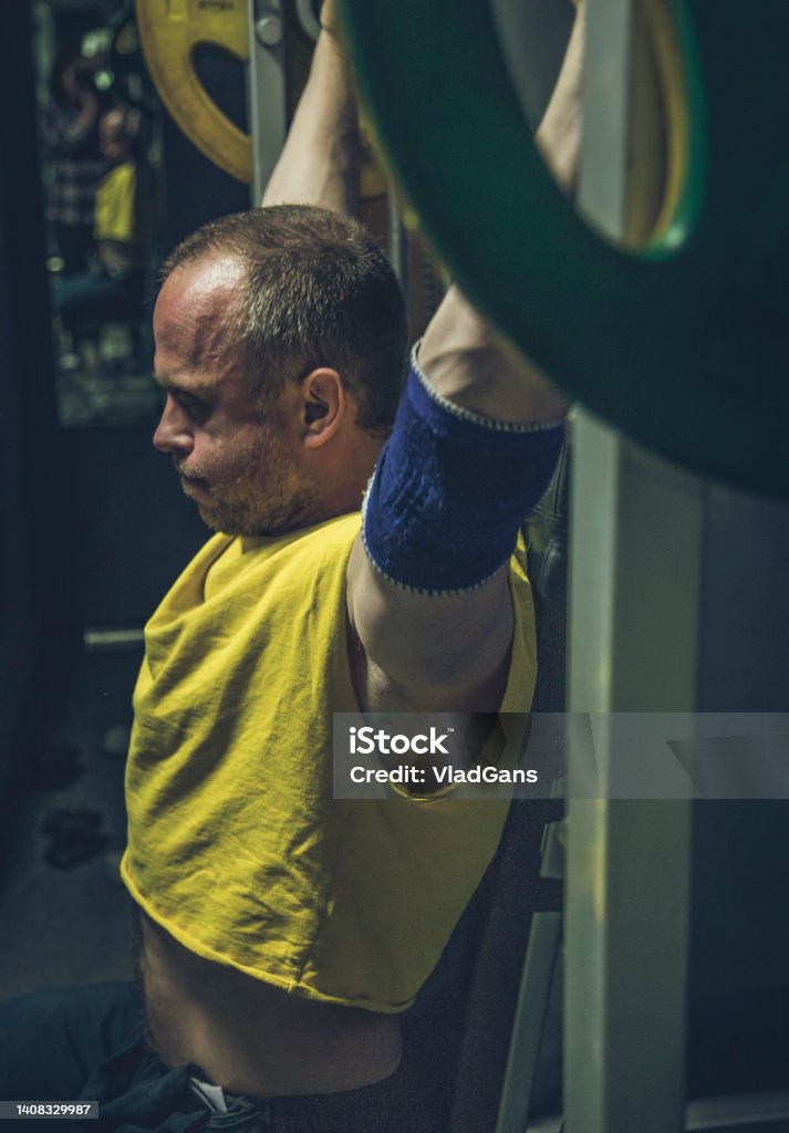 Adult man trains shoulders Adult man trains deltoid muscles at the smith machine 40-44 Years Stock Photo