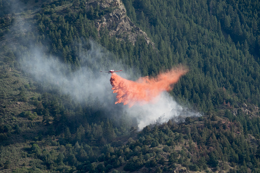 Flying low, a fire fighting plane drops fire retardant on the Snowcreek fire near Highway 285 on July 12, 2022 in a pine forest in the Rocky Mountain foothills of Morrison, Colorado.