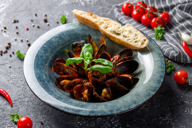 istock Mussels in tomato sauce on blue plate with basil on grey table 1408343579