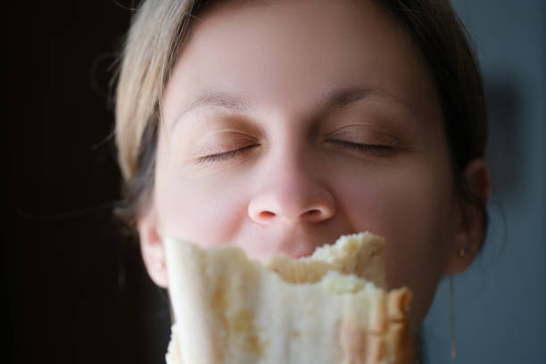 mujer olfateando delicioso trozo fragante de pan blanco - smelling bread bakery women fotografías e imágenes de stock