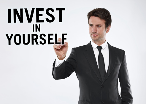Businessman writing “Invest in yourself” on a touch screen