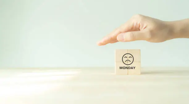 Avoid feeling down on blue Monday concept. Protection wooden cubes with a sad face drawn. Monday blues, tired and fear of routine office work, depression or sadness worker, sleepy and frustrated.