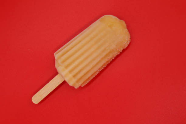 Orange popsicle stick isolated on red background. Bright color, summer mood