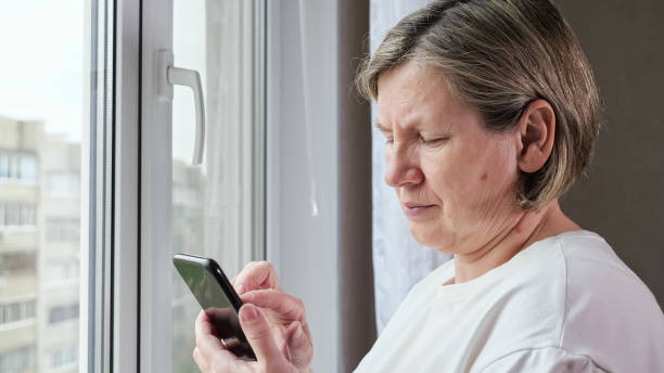istock Old woman scrolls through web pages on black smartphone 1408361069