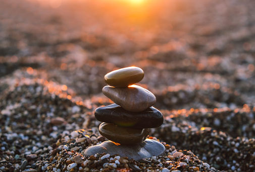 Pyramid of pebbles on the beach at sunset. Concept of zen, stability, harmony, balance and meditation, copy space.