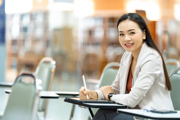 istock asia woman Teacher taking notes from tablet at library at university 1408364724