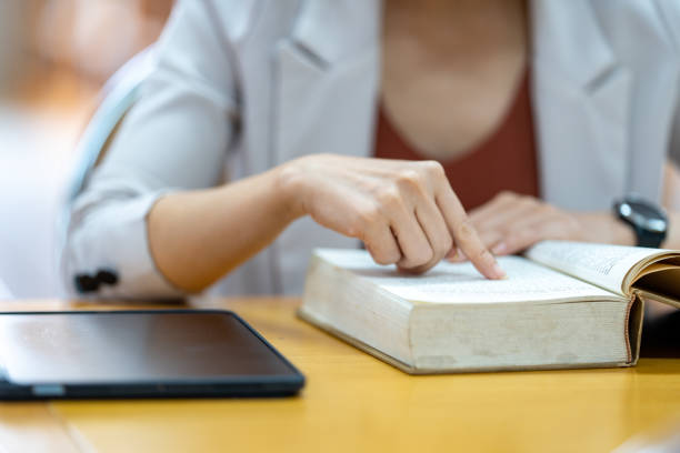 istock Young woman reading a book in library at university 1408364764