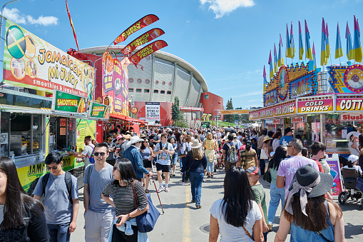 Opening of the most anticipated event in Calgary Canada on July 07, 2022 Stampede Park crowd of people with sunglasses and short shirts from all over the world walking between the summer heat of the time large food stalls with colored flags the stadium in the bottom