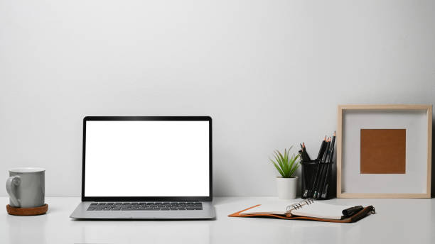 istock Mock up laptop computer, coffee cup, stationery and picture frame on white table. 1408365798