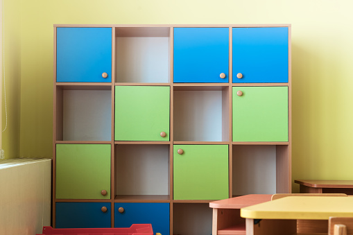 Multi colored wooden cabinet with cells stands in classroom