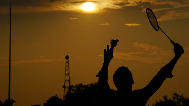 istock silhouettes. man play badminton in the park 1408368925