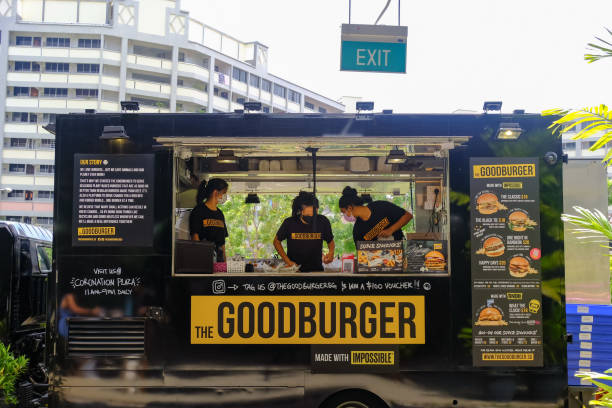 singapore 2022mar staff prepara hamburger e patatine fritte in un camion di cibo in un evento al sunday social market. i camion di cibo stanno iniziando a guadagnare popolarità qui. - dining burger outdoors restaurant foto e immagini stock