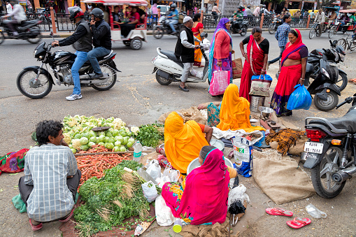 Jaipur, India - January 7, 2020: Women buying vegetables on the street in Jaipur, Rajasthan, India. Jaipur is the capital and largest city of the Indian state of Rajasthan in Northern India.