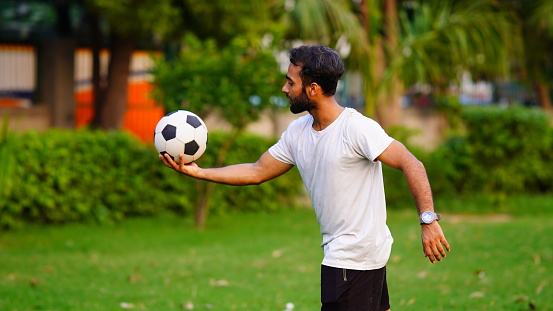 man holding football in green park
