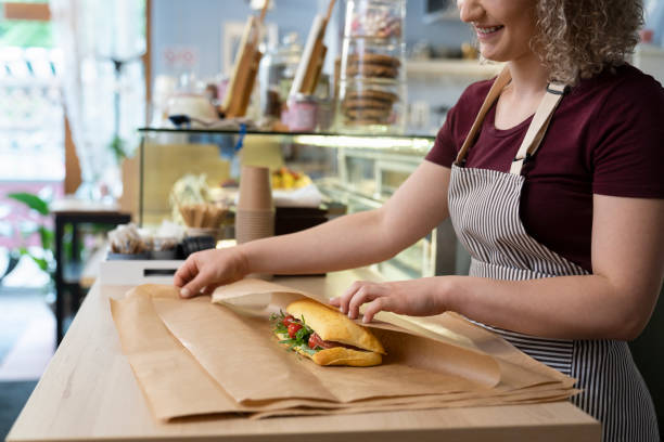istock Young caucasian waitress packing prepared sandwich in commercial kitchen 1408370280