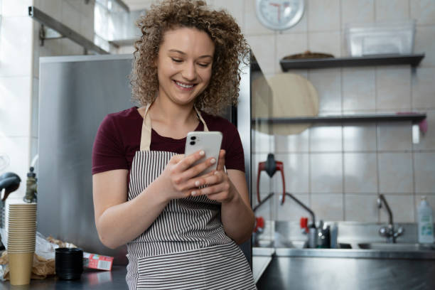 istock Young caucasian waitress using phone in the kitchen 1408370287