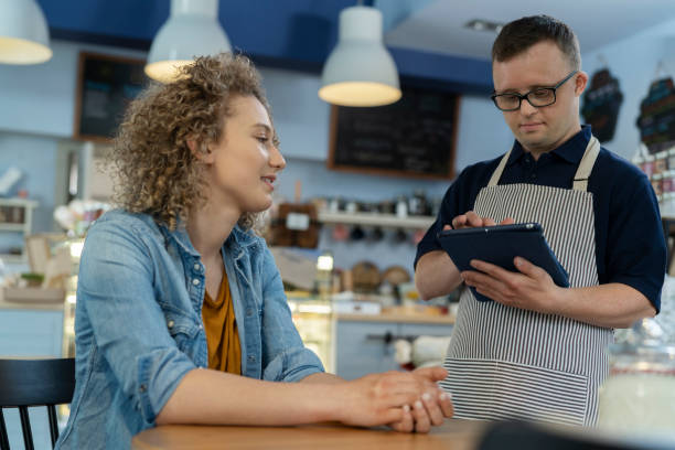 istock Caucasian waiter man with down syndrome discussing menu with the client 1408370409