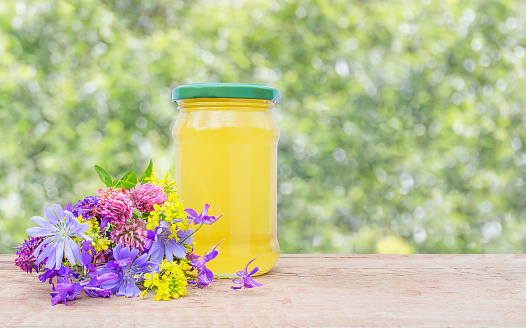 Background with a jar of honey and a bouquet of wild flowers with copy space