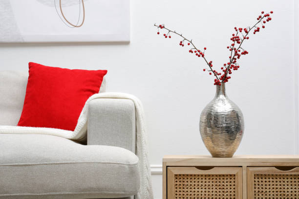 Hawthorn branches with red berries on wooden commode in living room