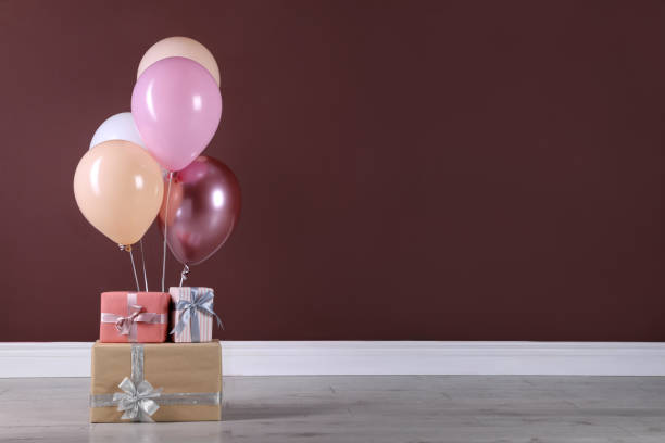 istock Many gift boxes and balloons near brown wall. Space for text 1408374267