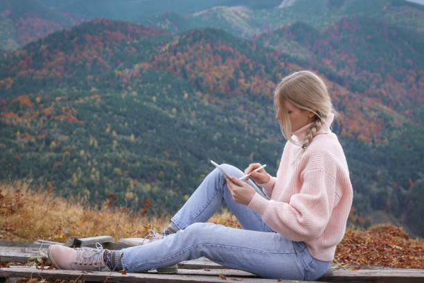 istock Young woman drawing on tablet in mountains, space for text 1408374603