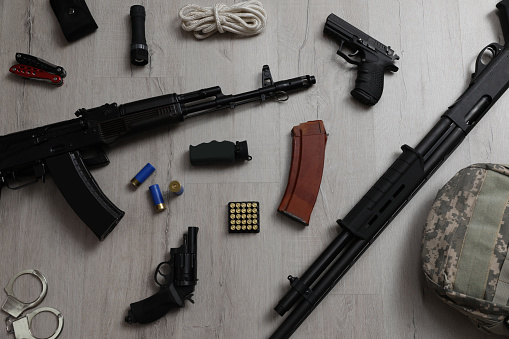 Flat lay composition with different guns and military knapsack on wooden background