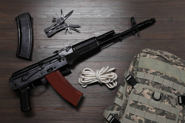 istock Flat lay composition with gun and military knapsack on wooden table 1408375509