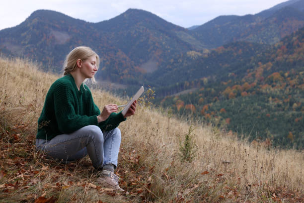 istock Young woman drawing on tablet in mountains, space for text 1408375522