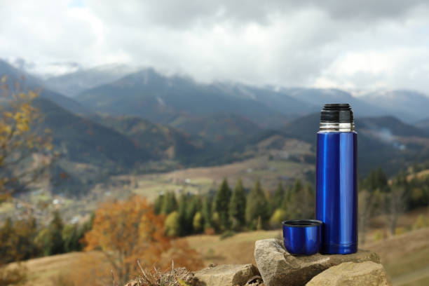 istock Blue thermos on rock in mountains, space for text 1408375843