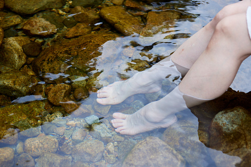 The feet of a young woman immersed in the river