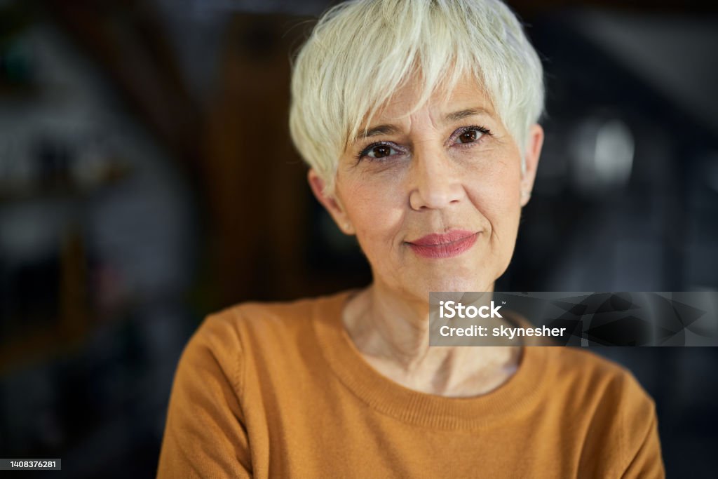 Smiling mature woman with short hair. Portrait of smiling senior woman with short hair looking at camera. Mature Women Stock Photo