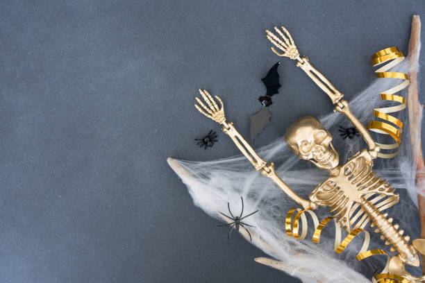 istock Creepy and funny halloween composition with white cobweb, spiders, bats and golden skeleton over gray concrete background with copy space for text. Party invitation card template 1408376293