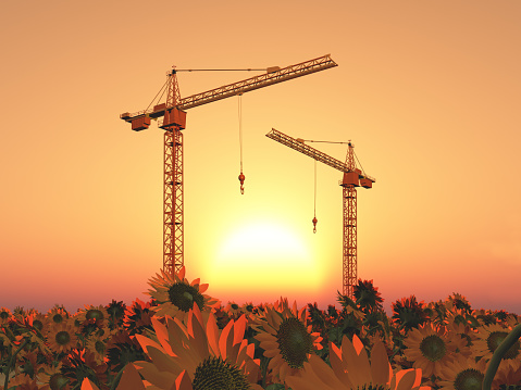 Computer generated 3D illustration with construction cranes in a landscape at sunset