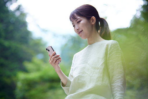 A young Japanese woman with a smartphone in nature