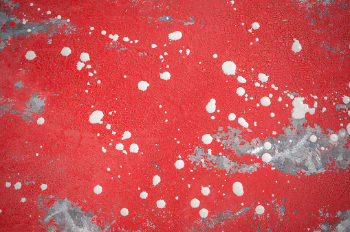 red background with small white drops of acrylic paint and damaged surface. Abstract art background with damaged aged surface.