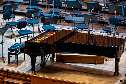 Grand Piano on stage in empty concert hall, no people.
