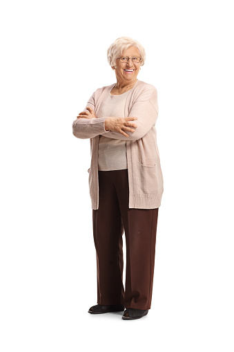 Full length portrait of an elderly woman smiling and posing with crossed arms isolated on white background
