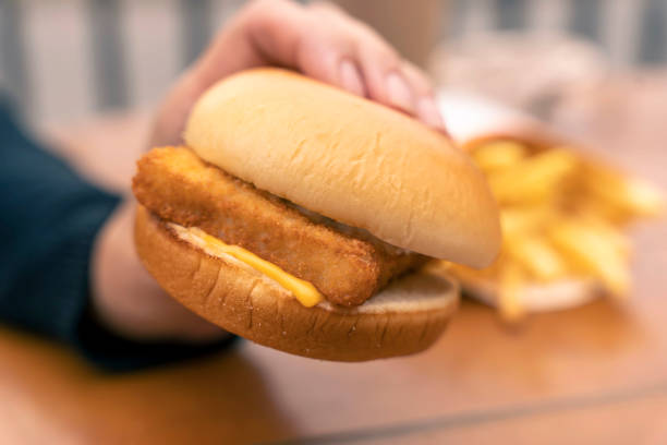a woman's hand holds a burger with fish fillet. Fast food, a snack stock photo