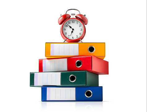 Multicolor ring binders with red alarm clock isolated on white background.