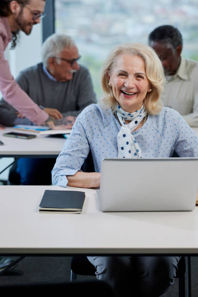 istock A happy female senior student sits in a classroom and does an assignment on the laptop while smiling at the camera. 1408386205