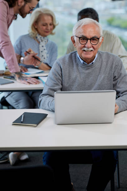 istock A senior man is smiling while having a retraining class with a multicultural group of senior people in the classroom. 1408386428